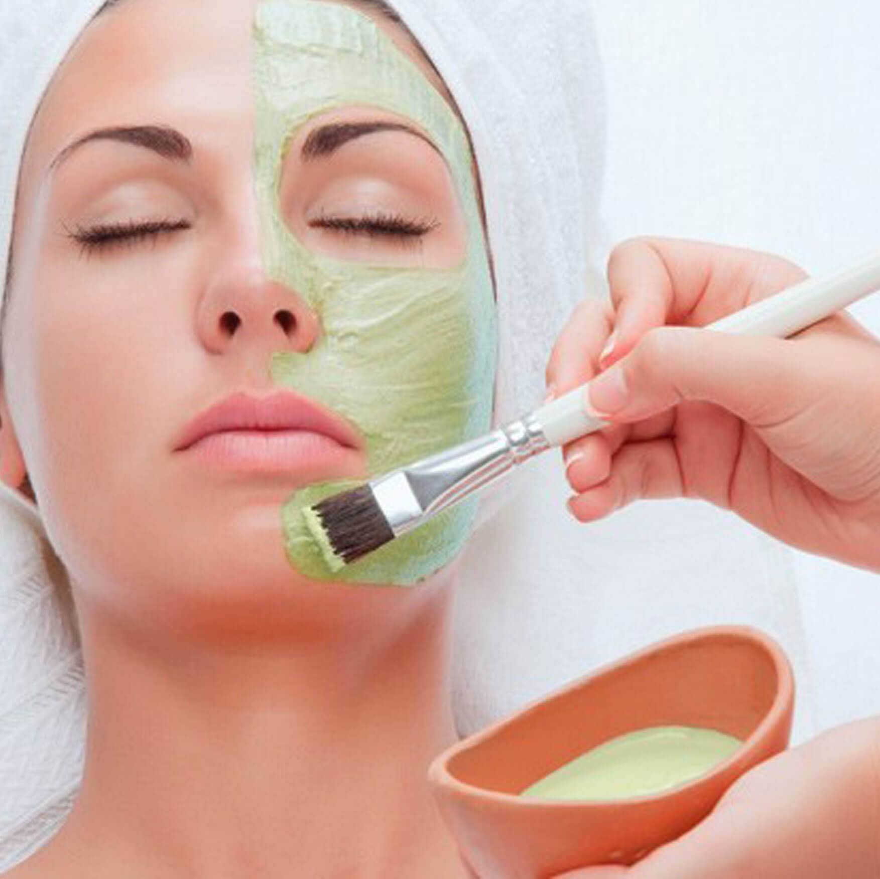 Grüne Gesichtsmaske wird auf Gesicht aufgetragen